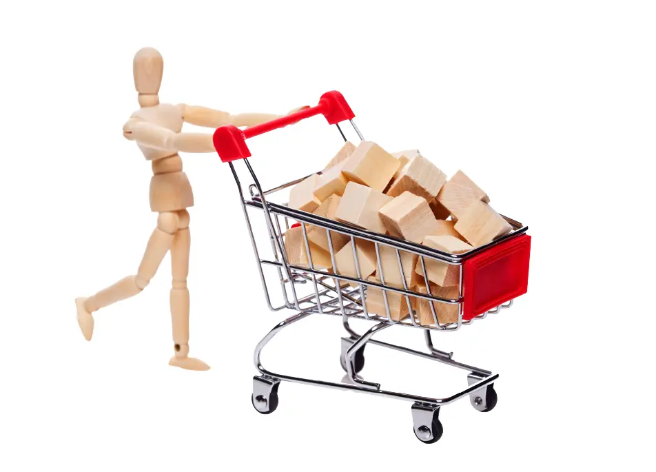 A wooden figure pushing a shopping cart filled with wooden boxes.